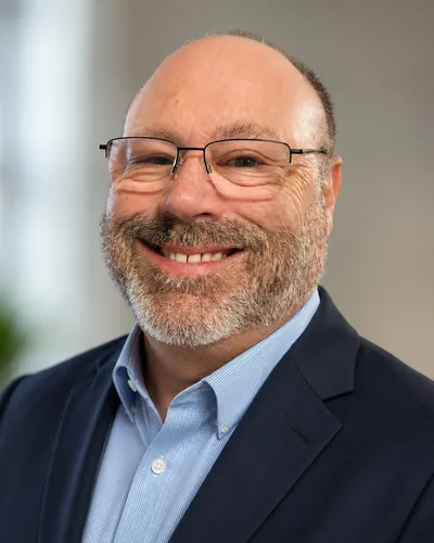 Jeff Weisblatt, owner and senior agent at Tierra Vista Health, smiling in a navy suit jacket and light blue shirt